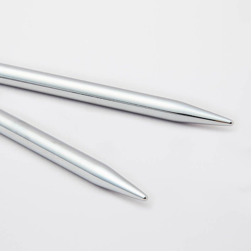 Two silver metal knitting needles on a light gray background