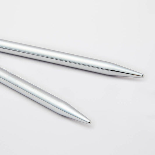 Two silver metal knitting needles on a light gray background